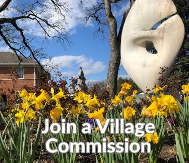 A photo of yello daffodils in front of a sculpture at Village Hall