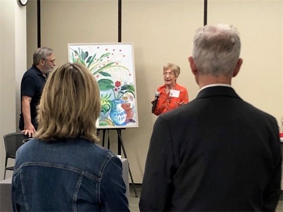 People watching an artist talk about her painting at a Village art show.