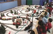 Children look at a holiday model train display with a curvy track