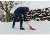 A man using an orange shovel to clear a walkway of snow