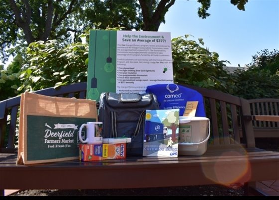 Photo of $100 restaurant gift card, Farmers Market tote, compost pail and other prizes on a bench at Village Hall
