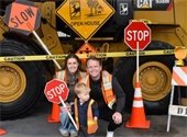 Family posing at a photo booth with trucks and street signs