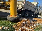 Photo of a vacuum truck sucking up leaves left in a line along the curb with a little snow on the ground