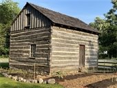 Photo of the Caspar Ott log cabin at the Historic Village with a garden