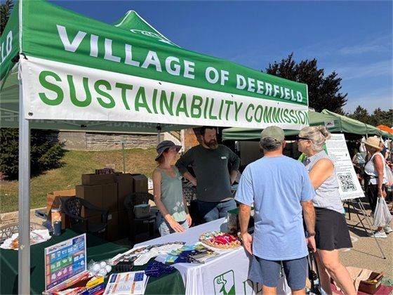 Photo of Sustainability Commissioners interacting with residents at a booth at the Farmers Market
