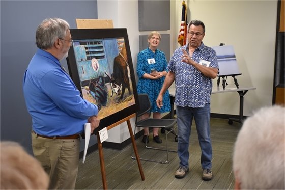 An artist talks about his painting of a cowboy and bull at a rodeo