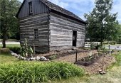 Photo of the Ott family log cabin with a garden at the Historic Village